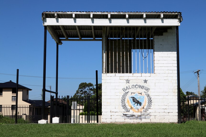 A white brick standalone ticket booth building with the Balgownie Rangers logo printed on the brick work.