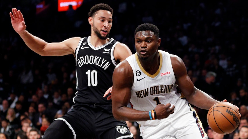 Zion Williamson of the New Orleans Pelicans dribbles past Brooklyn Nets' Ben Simmons during an NBA game.