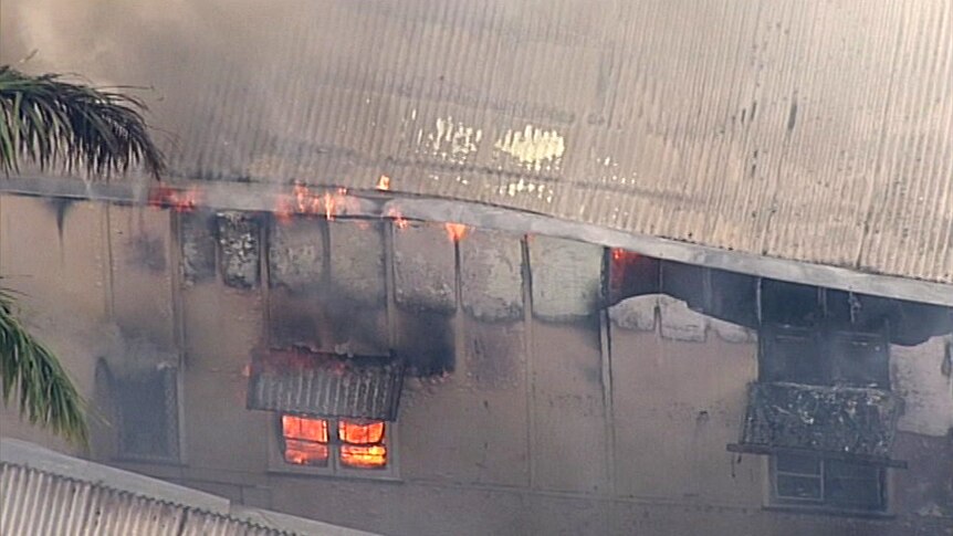 An aerial photo showing flames coming from under the roof of a building destroyed by fire at South Brisbane.