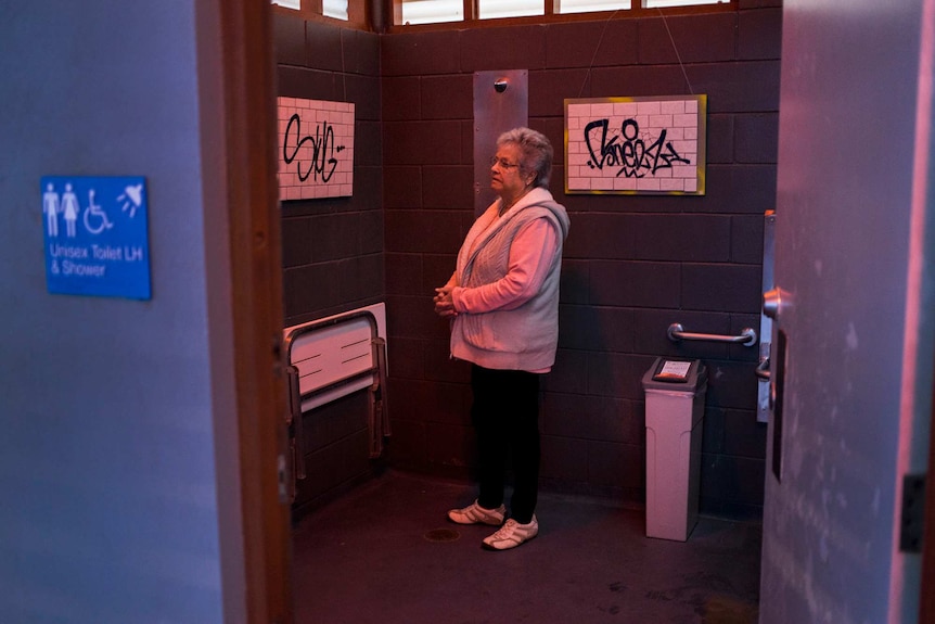 Woman views art in toilet.