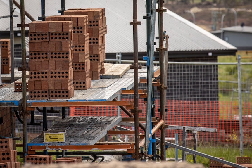 Stacks of bricks, scaffolding and temporary fencing.