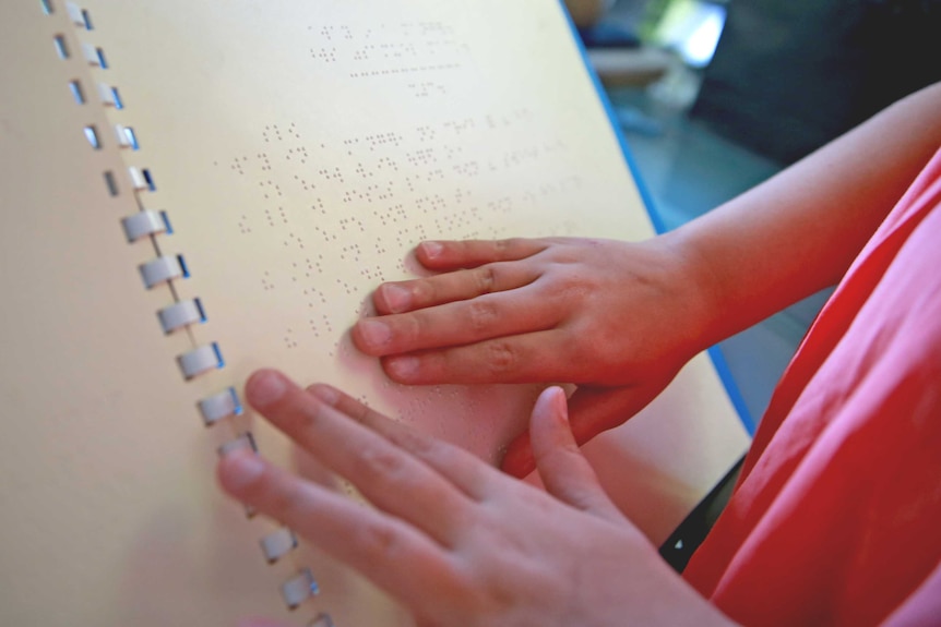 Lilly Cascun reading Away in a manger in brail.