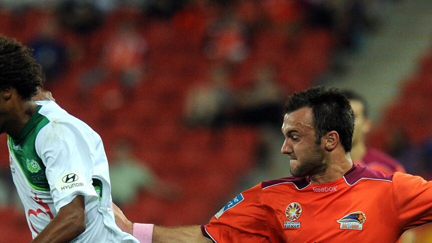 Former Roar player Isaka Cernak battles for possession with Ivan Franjic.