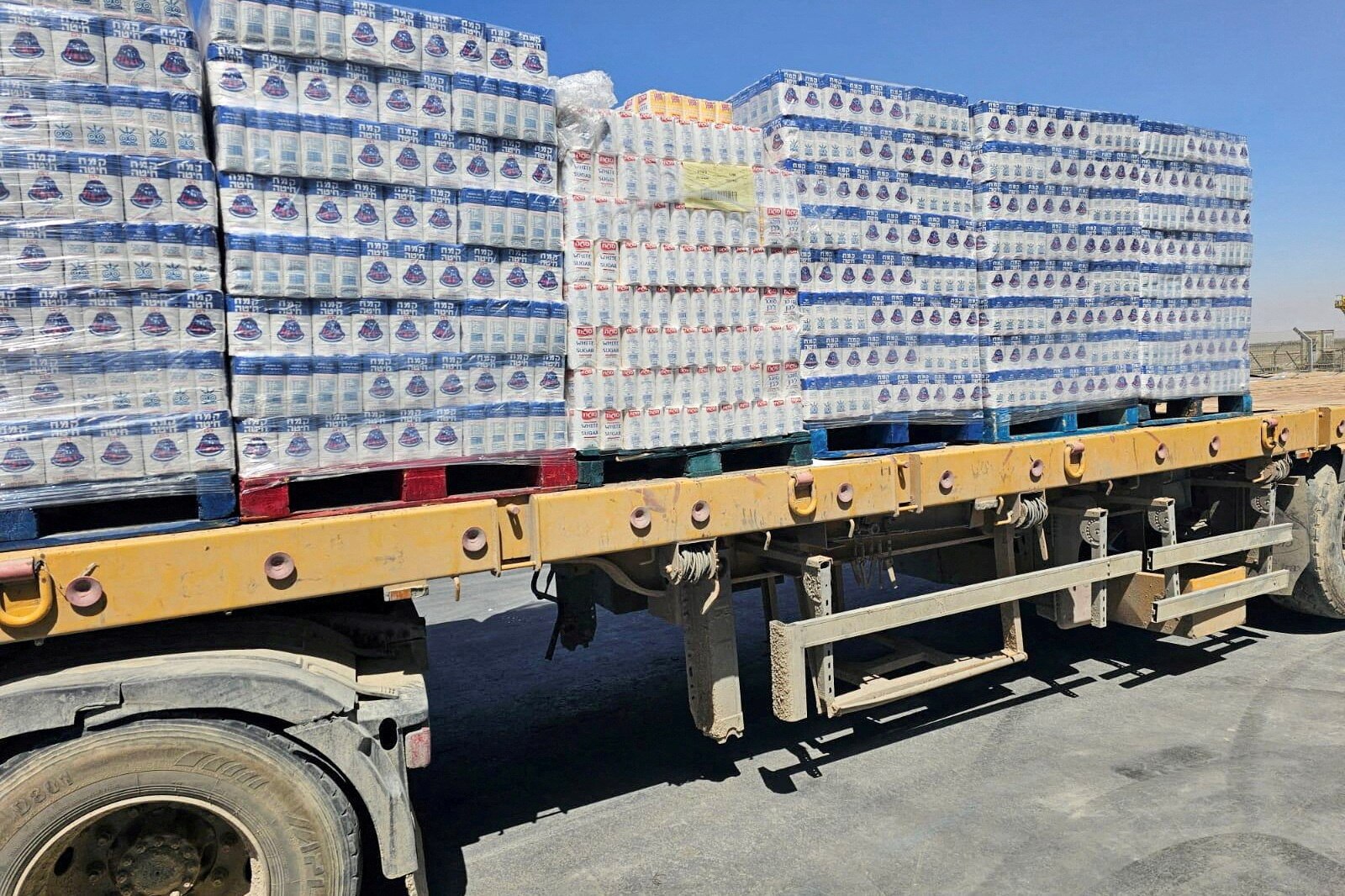 Pallets of food aid can be seen on the back of a flat bottom truck.