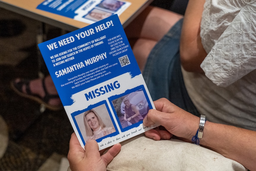 a person holding a blue flyer with a picture of Samantha Murphy and some information about her disappearance. 