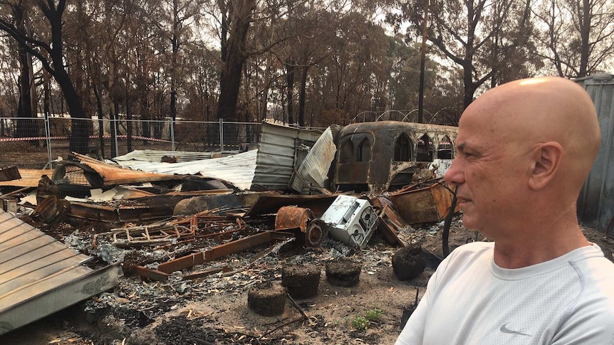 Geoff Belmore standing next to wreckage of his home.