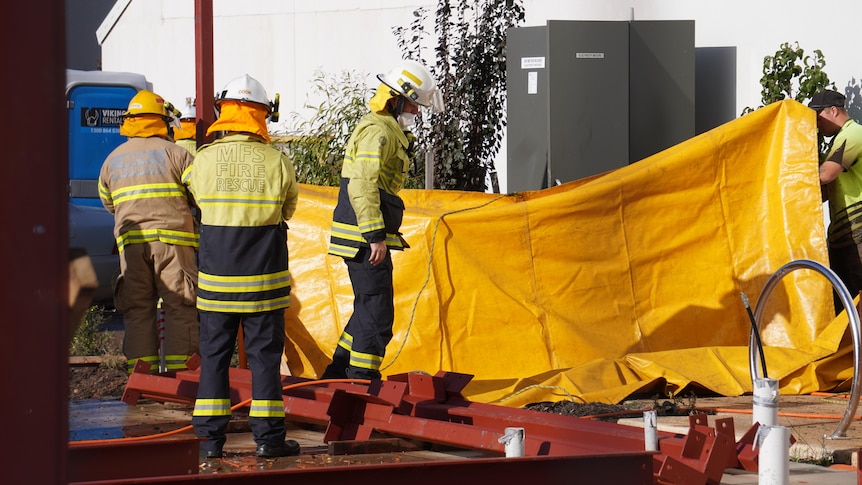 Firefighters holding a yellow sheet in front of an electrical box