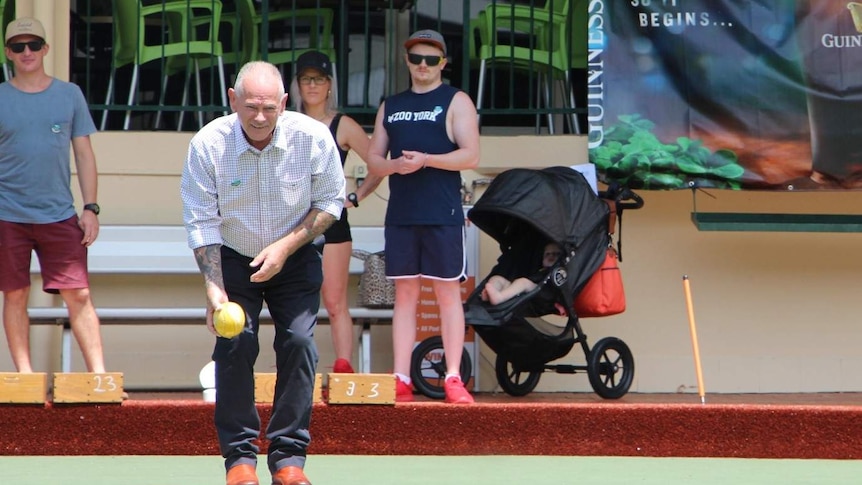 A man about to bowl with three people standing behind him