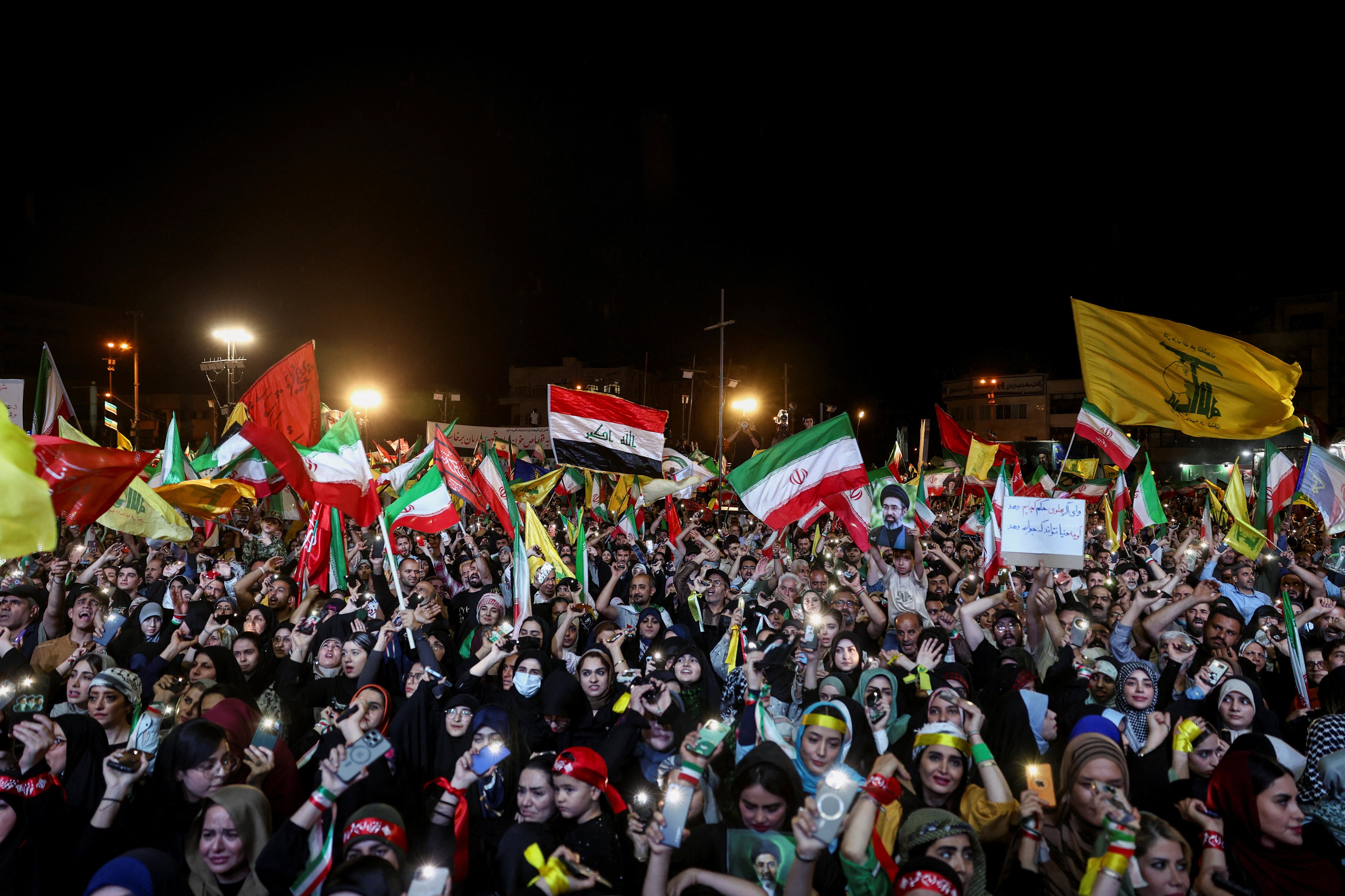 A huge crowd of people waving Iran, Hezbollah and other flags at a rally in Tehran.