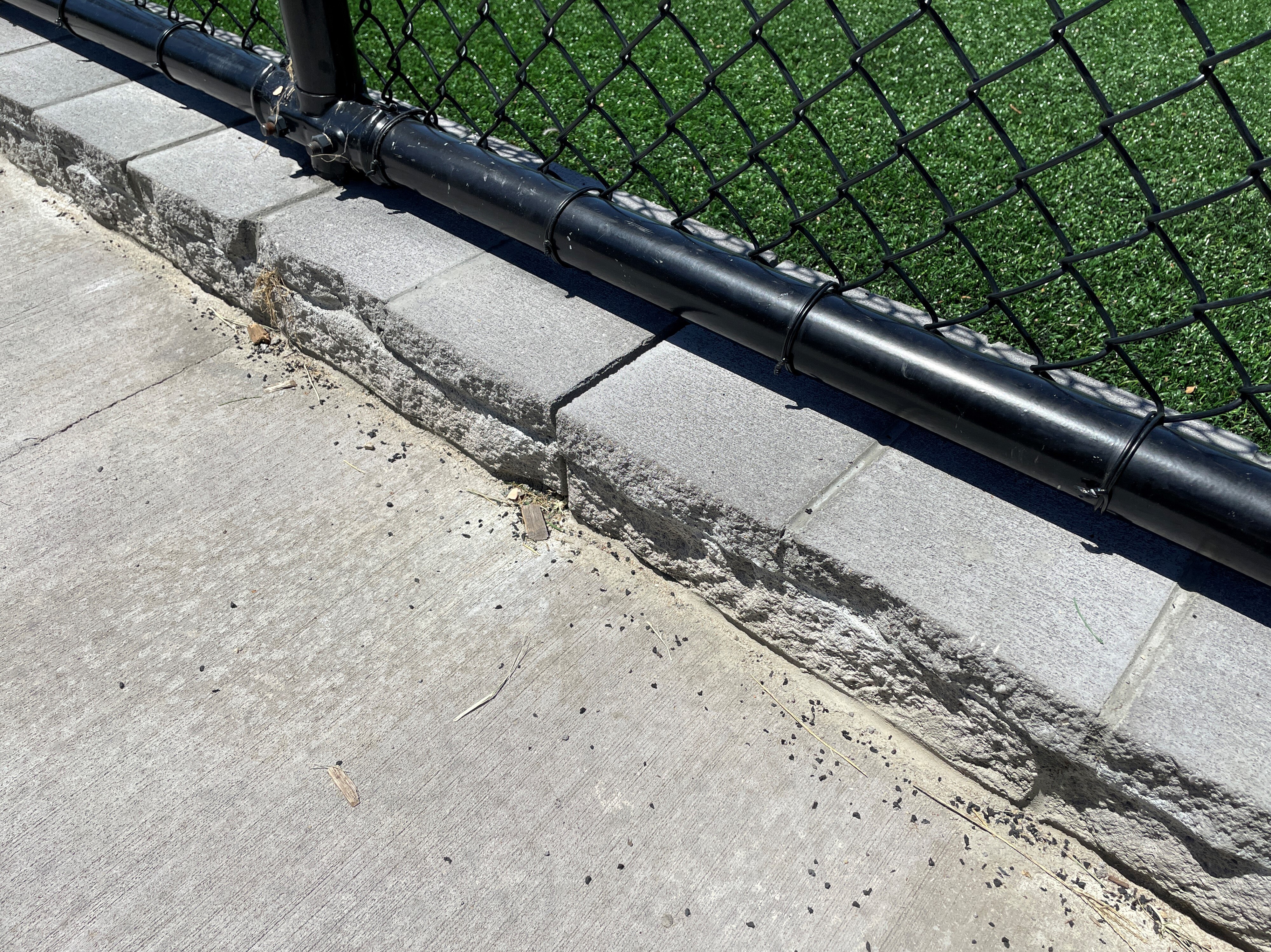 Tiny crumbs of rubber on a footpath beside artificial turf.