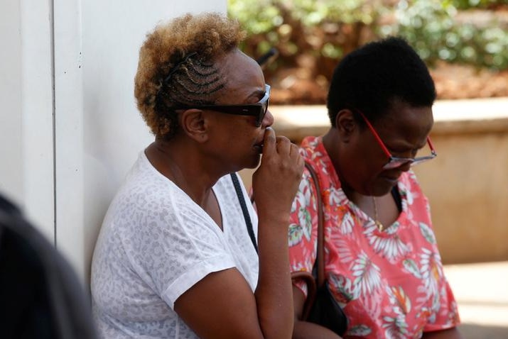 A tearful woman waits with her hand to her mouth as she sits while waiting for news of plane crash victims.