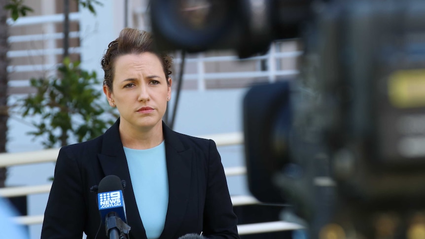 A woman stand in front of a news TV camera