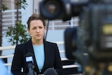 A woman stand in front of a news TV camera