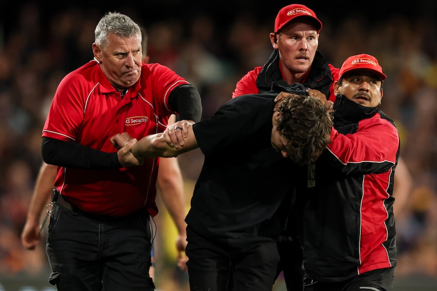 A pitch invader is taken from the field by security at Adelaide Oval.
