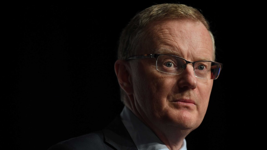 Reserve Bank of Australia governor Philip Lowe is pictured against a black background as he gives a speech.