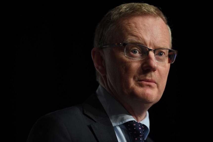 Reserve Bank of Australia governor Philip Lowe is pictured against a black background as he gives a speech.