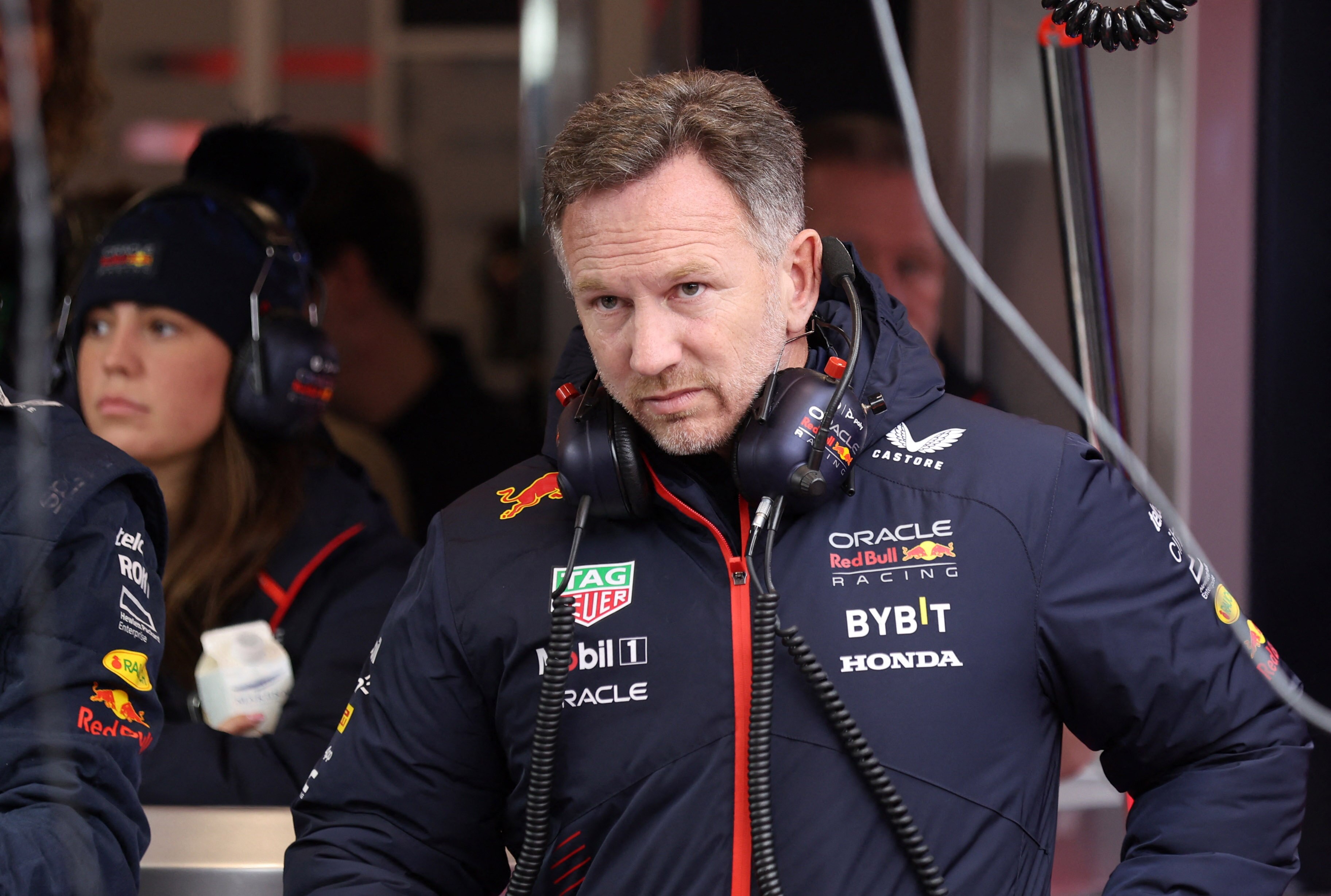 Christian Horner, in a Red Bull branded jacket with headphones around his neck, in the pit garage.