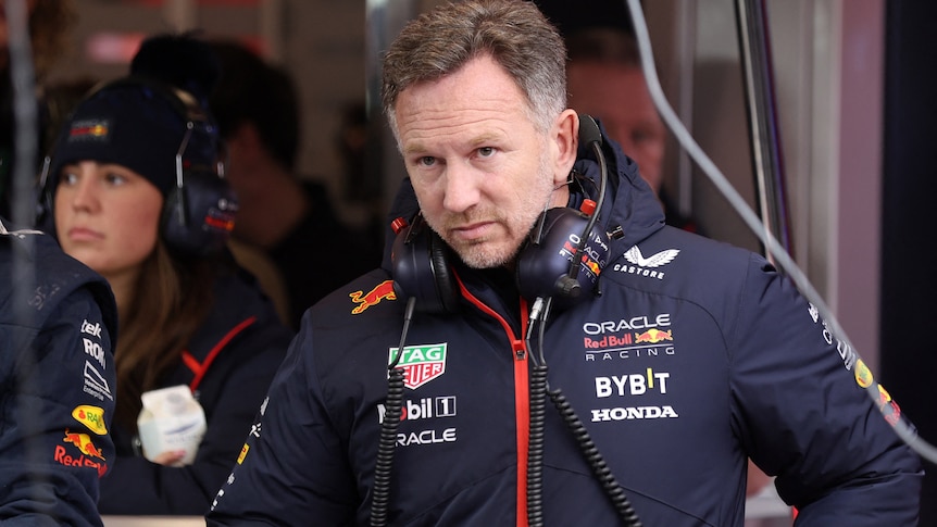 Christian Horner, in a Red Bull branded jacket with headphones around his neck, in the pit garage.