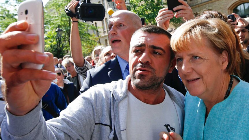 A migrant takes a selfie with Angela Merkel