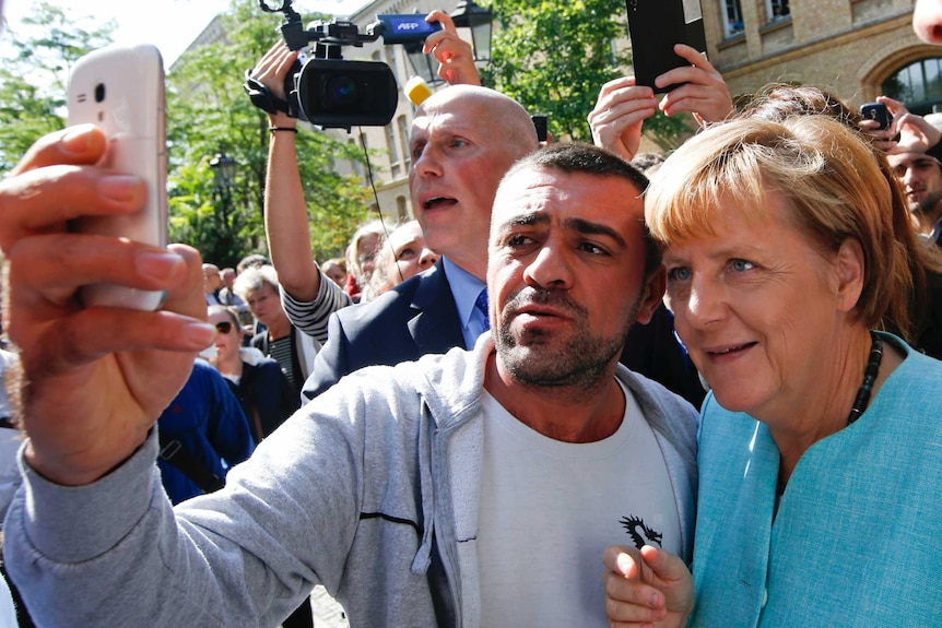 A migrant takes a selfie with Angela Merkel