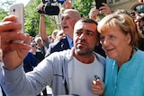 A migrant takes a selfie with Angela Merkel