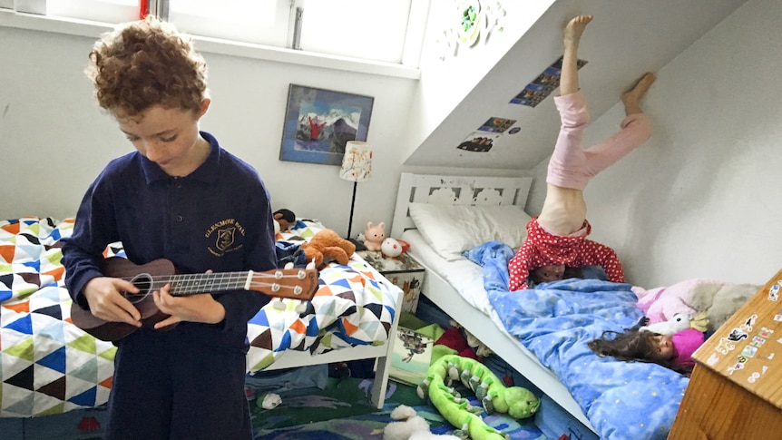 Two children much around in a bedroom.