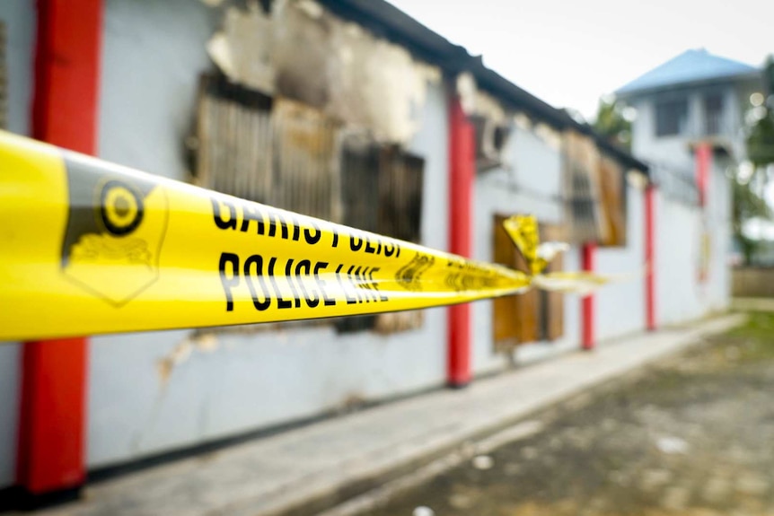 Police tape surrounds a fire-damaged building West Papuan jail where prisoners escaped during protests.