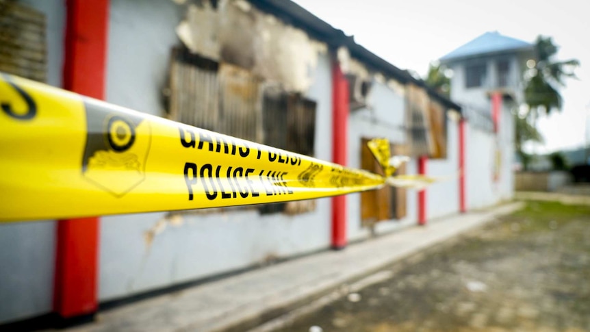 Police tape surrounds a fire-damaged building West Papuan jail where prisoners escaped during protests.