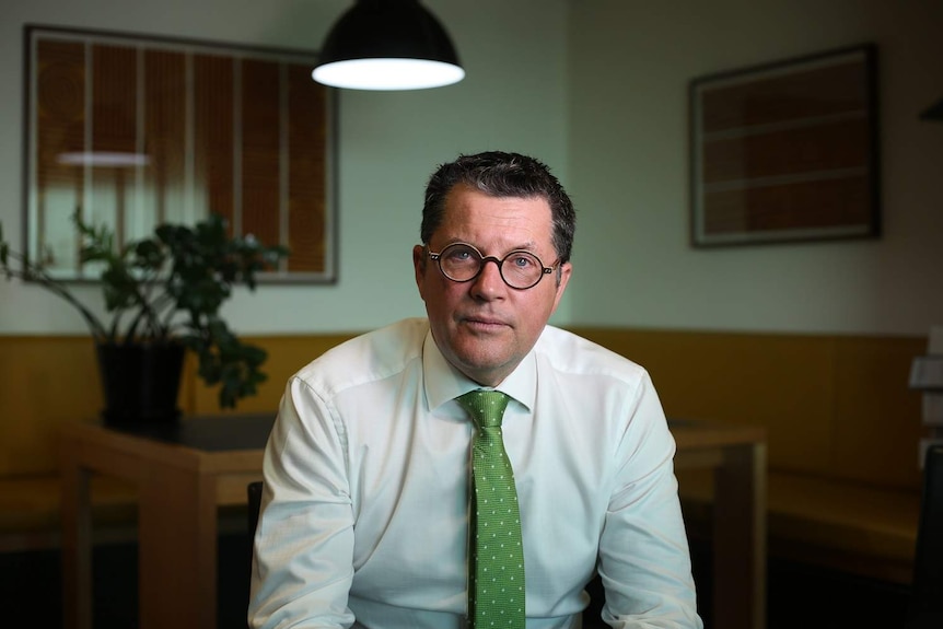 Damien Atkinson sits at his office desk