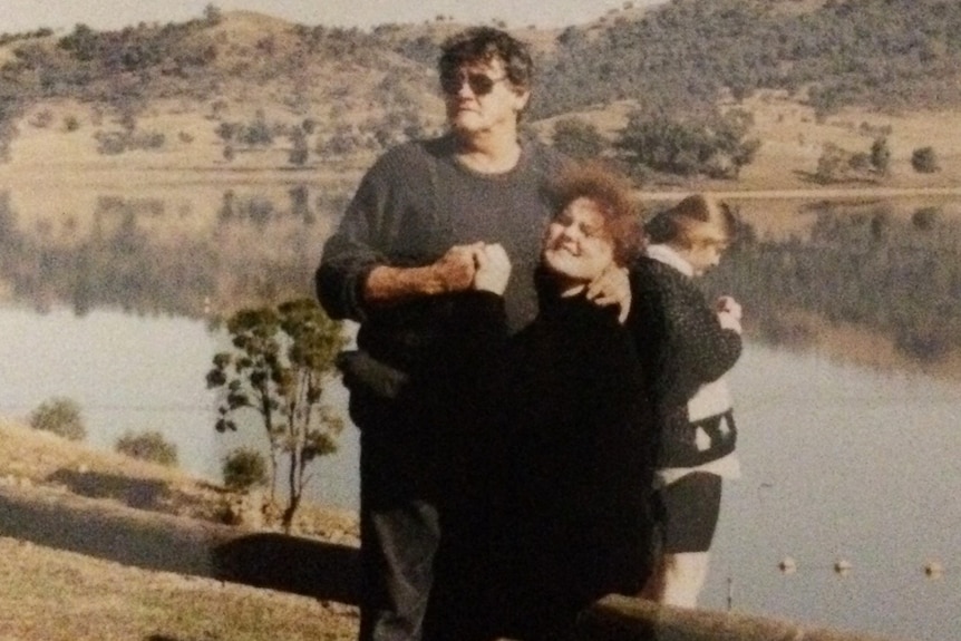 Bob Phillips hugging his daughter Merlesa beside a dam at a unknown location.
