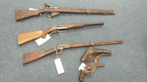 Four very old guns lying on a grey floor.