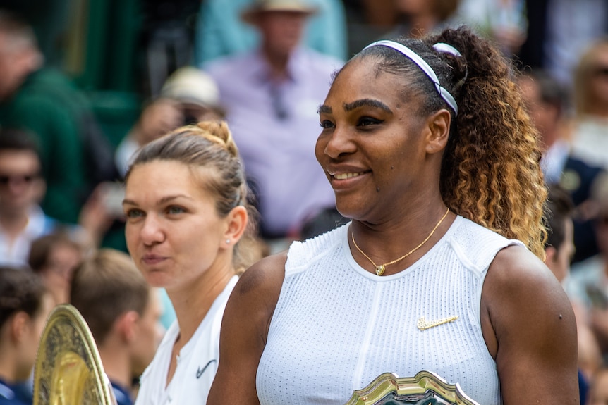 Serena Williams stands in front of Simona Halep