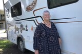 Beth Stephensen standing at the side of a white motorhome with darkened windows
