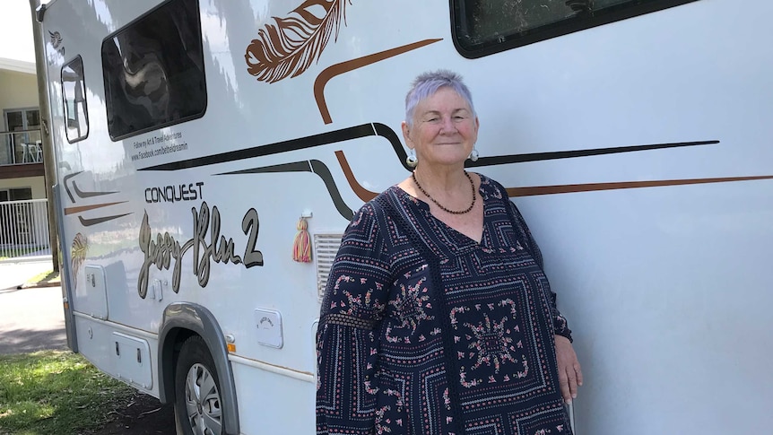 Beth Stephensen standing at the side of a white motorhome with darkened windows