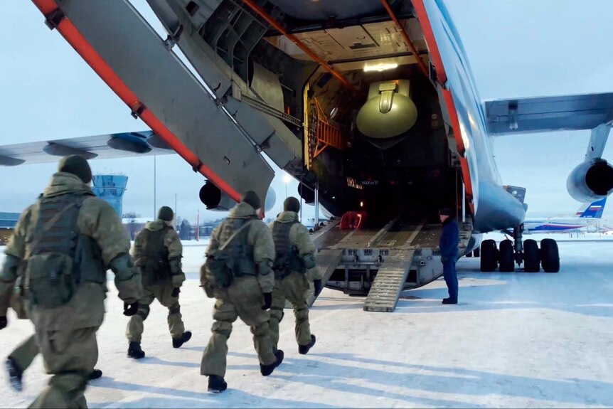 Russian peacekeepers board on a Russian military plane at an airfield.