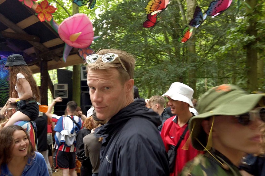 Reporter Tom Tilley looks back while in crowd of people near a stage