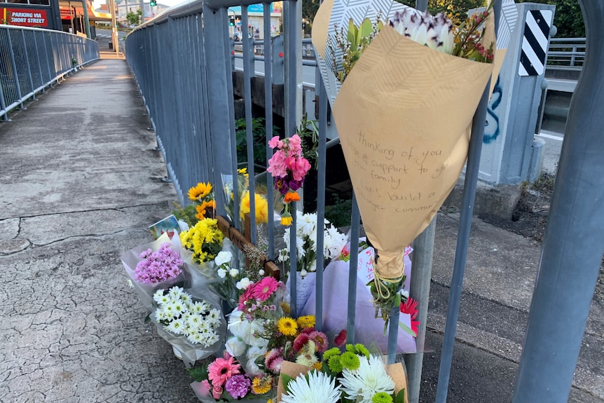 Flowers beside a bridge. A message of support is visible on the wrapping.