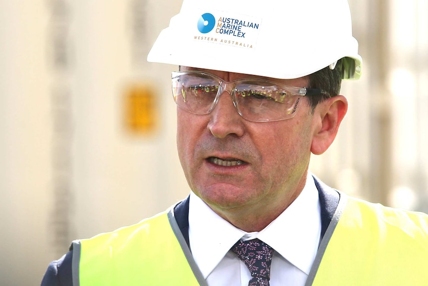A tight head and shoulders shot of  Mark McGowan wearing a hard hat, safety glasses and a yellow hi-vis vest.