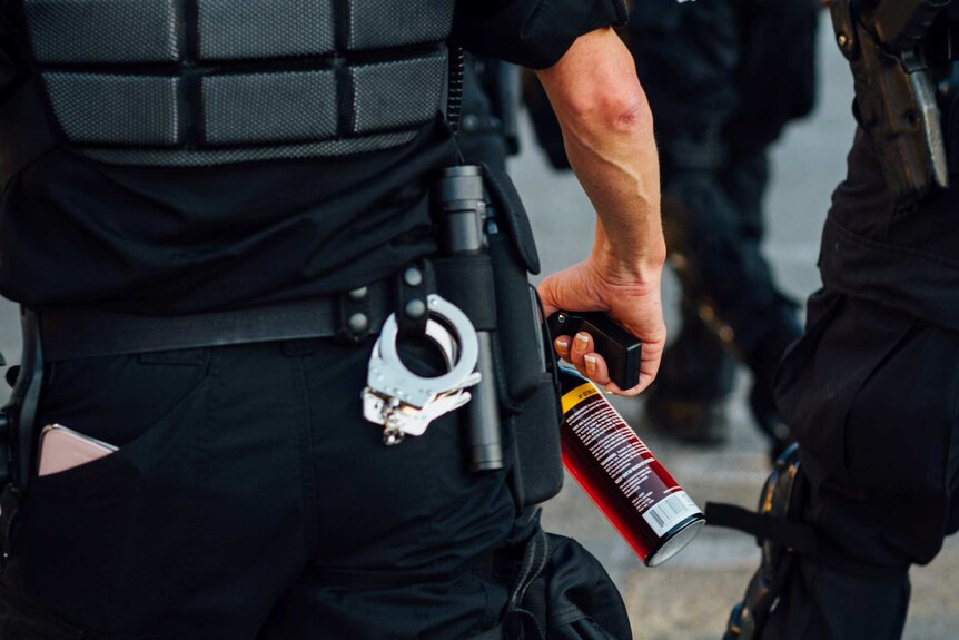 A police officer holds a can of pepper spray at a protest in Seattle in 2016.