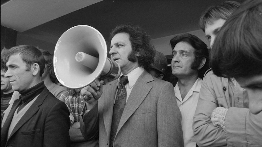 A black and white photo of a man in suit with a megaphone.