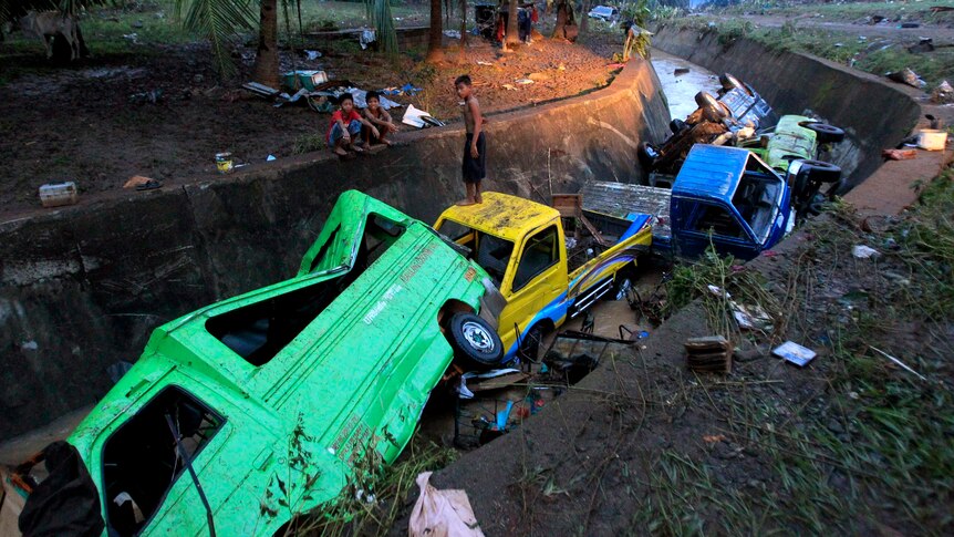 Damaged vehicles washed away by flash floods caused by Typhoon Washi lie in a ditch.