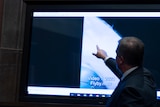 A man points at a TV screen showing footage of an unidentified flying onbject