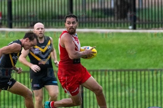 Indigenous man holding ball in football match 