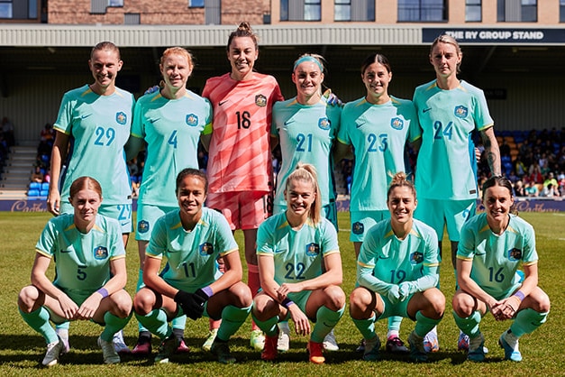 A women's soccer team wearing light blue poses for a photo before a game