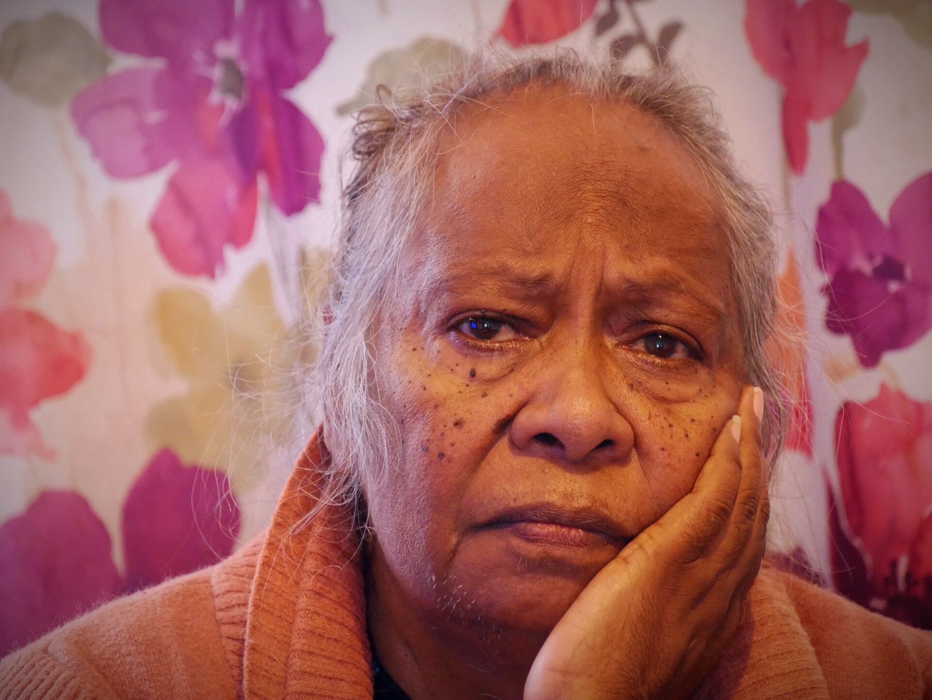 Close up photo of Lucy's face with pink flower backdrop