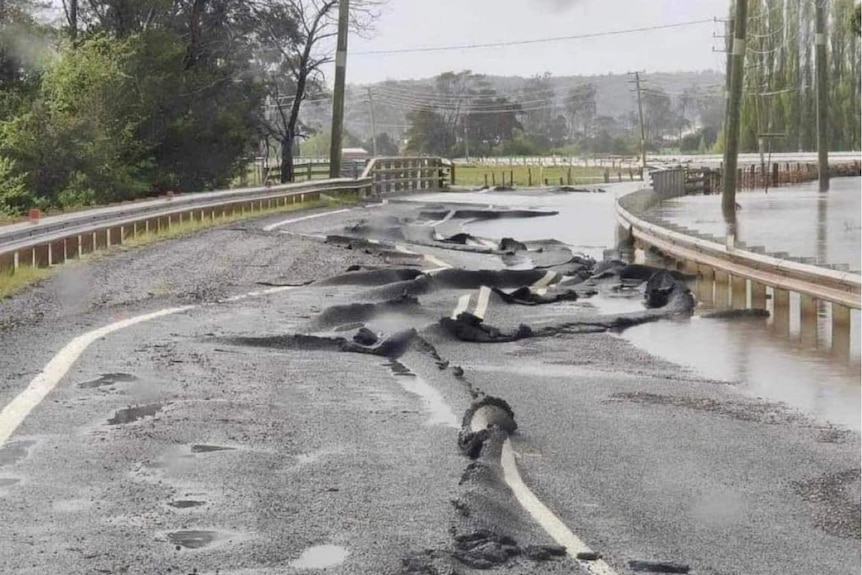 A road is buckled and warped by floodwaters.