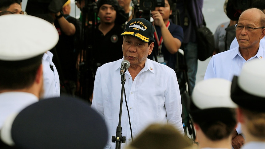 Rodrigo Duterte, wearing a black and yellow "HMAS Adelaide" cap, speaks to members of the Australian Navy.