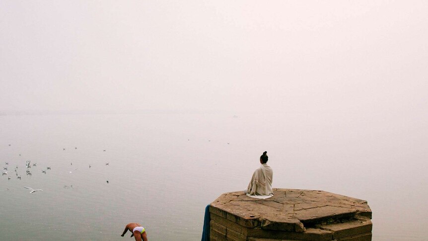 A woman meditates on the banks of the Ganges
