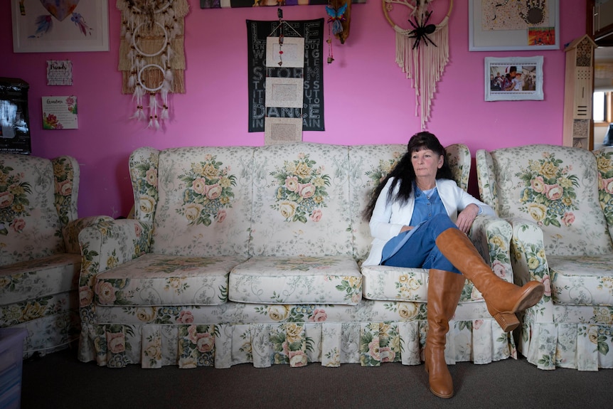 A woman with long black hair sits on a floral couch