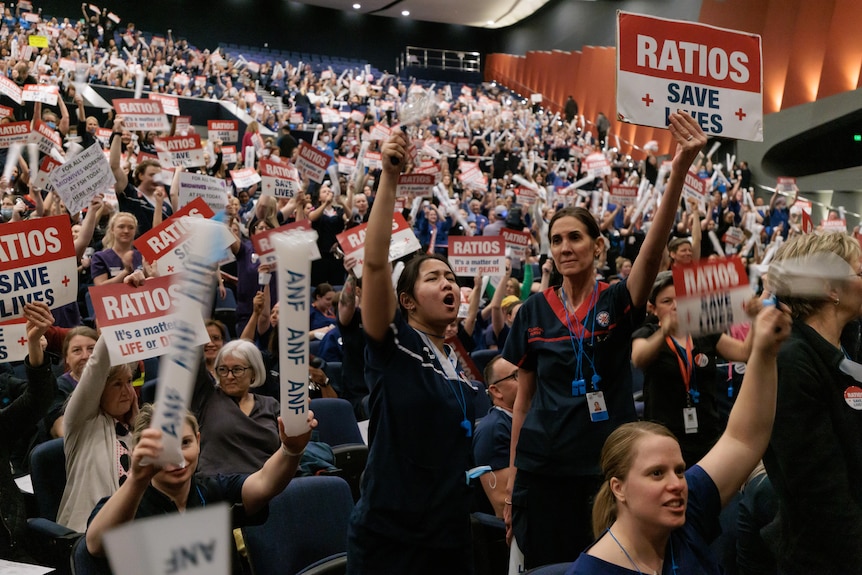 A large crowd of nurses holding signs calling for nurse-to-patient ratios. 